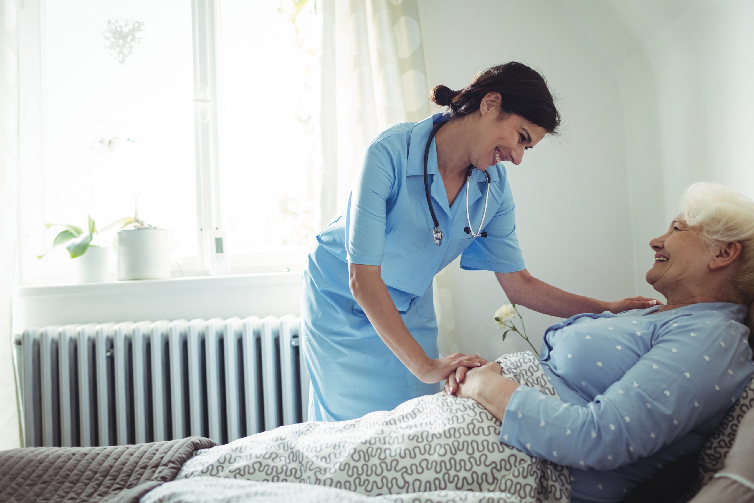 Nurse interacting with senior woman on bed